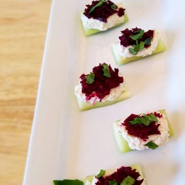 7 Cucumber Feta Bites with Beets and Basil displayed on a white rectangle dish on a wood table