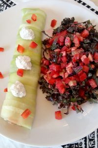 One Raw Vegan Salmon Roll and Red Kale Salad on a white plate on a white and black placemat