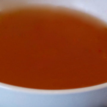 A close up of a white bowl with vegetable broth