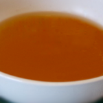 A close up of a white bowl with vegetable broth